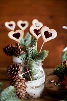 some cookies are in a jar with pine cones