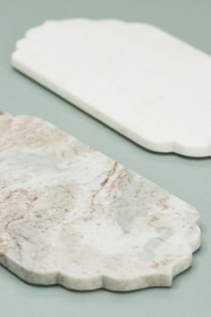 two pieces of white marble sitting on top of a green table next to each other