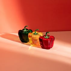 three colorful peppers sitting on top of a white counter next to an orange and red wall