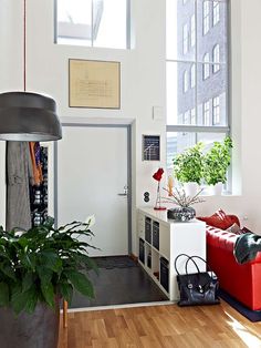 a living room filled with furniture next to a window covered in plants and potted plants