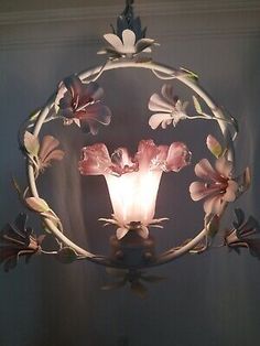 a light that is hanging from the ceiling with flowers on it and leaves around it