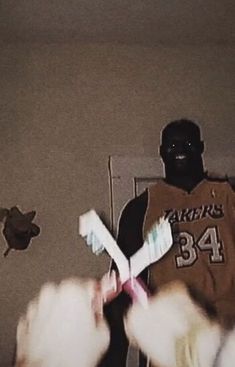 a person with toothbrushes in their hands standing next to a stuffed animal on a bed