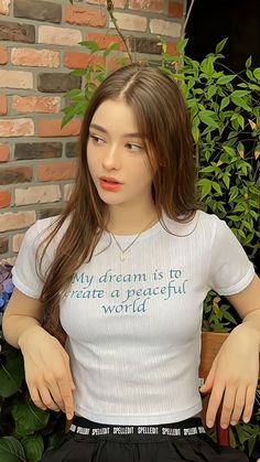 a woman is sitting on a bench with her hands in her pockets and wearing a t - shirt that says, my dream is to create a peaceful world