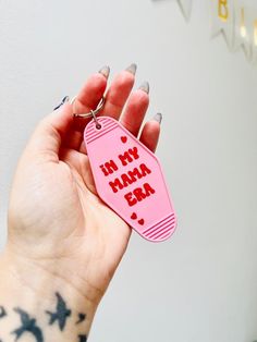 a hand holding a pink keychain that says i'm my mama exa