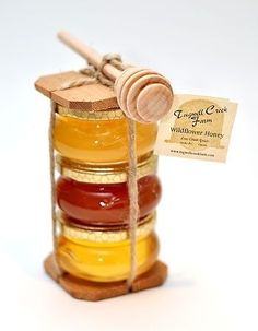 a jar filled with honey sitting on top of a white table next to a wooden stick