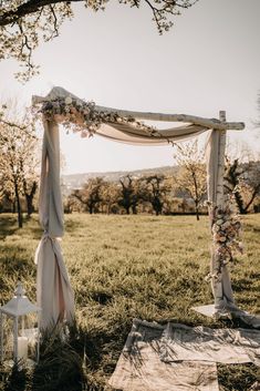 an outdoor wedding ceremony setup in the middle of a field with flowers and ribbons on it