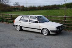 a white car parked in front of a wooden fence