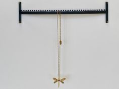 there is a necklace hanging on the wall next to a rack with two cross pendants