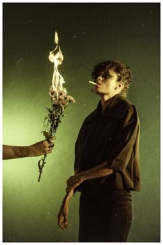 two people standing next to each other and one holding a stick with flowers on it