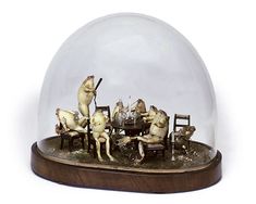 a group of cats sitting around a table under a glass dome on top of a wooden base