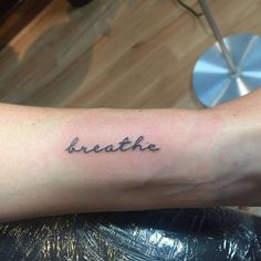 a person's arm with the word breathe tattooed on it, in black ink