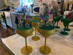 three wine goblets are sitting on a table in the kitchen with purple flowers