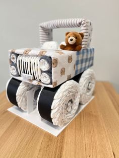 a teddy bear sitting in the back of a toy truck on top of a wooden table