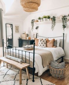 a bed room with a neatly made bed next to a wooden bench and mirror on the wall