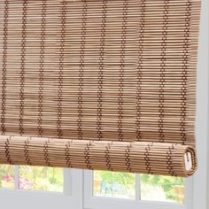 a bamboo roman blind in front of a window with the blinds pulled down and closed