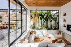 a living room with lots of white furniture and plants in the window sill area