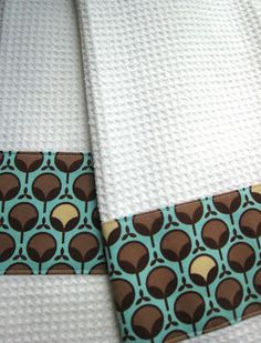 two white towels with brown and blue designs on them