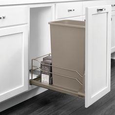 an open trash can in the middle of a white kitchen cabinet with gray flooring