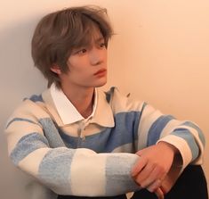 a young man sitting on the floor with his arms crossed