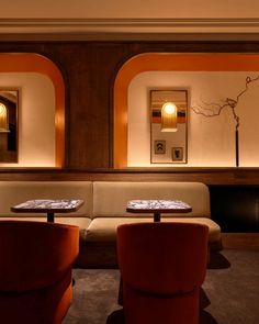 two tables and chairs in a room with orange walls on either side of the couches