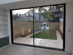 an empty room with large glass doors leading to the back yard, and a small garden area