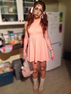 a woman dressed as a zombie holding a stuffed animal in her hand and wearing boots