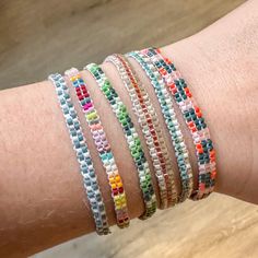 a woman's arm with several different colored bracelets on top of each other