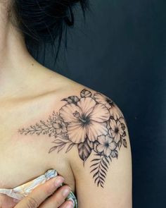 a woman's shoulder with flowers and leaves tattooed on her left side breast area