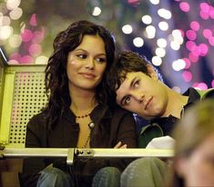 two people sitting next to each other in front of a firework display at night