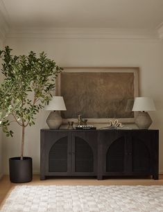 a living room with a tree and two lamps on the side tables in front of it