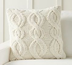 a white couch with a knitted pillow on it