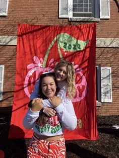 two girls standing in front of a red flag