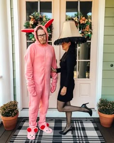 a man and woman dressed up in costumes standing on the front steps of a house