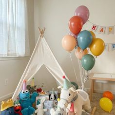 there is a teepee tent with balloons and stuffed animals on the floor next to it