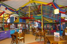 the inside of a children's play area with tables and chairs