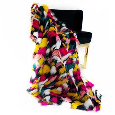 a multicolored fur stole sitting on top of a chair next to a black chair