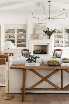 a living room filled with furniture and a fire place under a chandelier in front of a fireplace