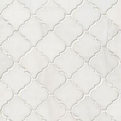 a white tile with an intricate design on the back wall and bottom part of it