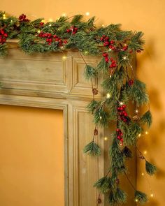 christmas garland with red berries and pine cones hanging from the mantle in front of a fireplace