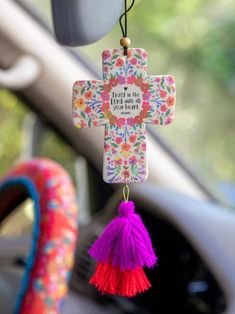 a colorful cross hanging from the dashboard of a car with a tasselled keychain