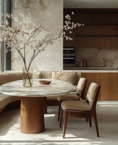 a round dining table surrounded by beige chairs