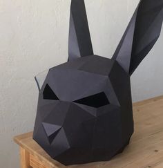 an origami rabbit mask sitting on top of a wooden table next to a white wall