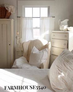 a bedroom with white linens and an old chair in the corner, next to a window