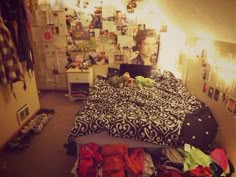 a woman sitting on top of a bed in a room filled with pictures and clothes