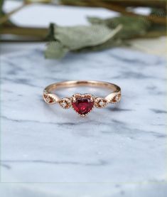 a red heart shaped ring on top of a marble table