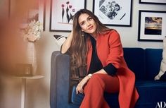 a woman sitting on top of a blue couch in a living room next to pictures