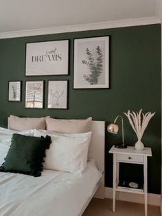 a bedroom with green walls and pictures on the wall above the bed, along with two nightstands