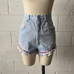 These 1990's vintage Extra Femme shorts are made from a light washed, cotton denim and white, nylon lace. Features a high waisted fit with floral ribbon around either leg and white, ruffled lace trim. Zips in front to a single button closure at the waist. A couple small tears in the lace that aren't noticeable but reflected in price. In overall excellent vintage condition with only minimal signs of wash and wear.   Marked a size 7, see below for measurements 25" waist 36" hips 13" rise 3" inseam Vintage Denim Blue Jeans For Summer, Vintage Cotton Jeans For Spring, Retro Cutoff Jean Shorts For Spring, Vintage Jeans With Frayed Hem For Spring, High Waist Cotton Bottoms With Lace Trim, High-waist Cotton Bottoms With Lace Trim, Spring Vintage Jeans With Frayed Hem, Light Wash Cotton Jean Shorts For Spring, Spring Light Wash Cotton Jean Shorts