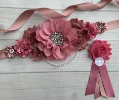 pink flowers and pearls are on the side of a white wall with ribbons around it