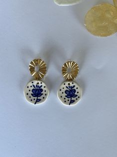 a pair of blue and white earrings sitting on top of a table next to a coin